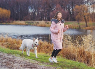 Ormanda koşan köpeği olan genç bir kız.