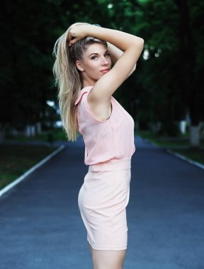 Young blonde model staying at the park  and looking at camera 