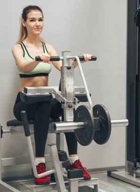 Genç kız spor salonunda egzersiz yapıyor.
