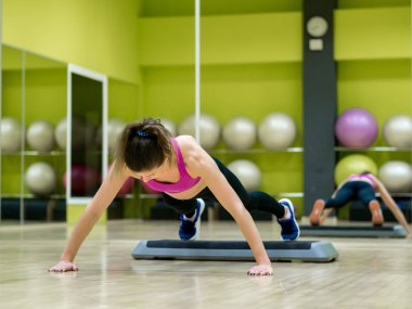 Genç model kız spor salonunda aynanın önünde egzersiz yapıyor. 