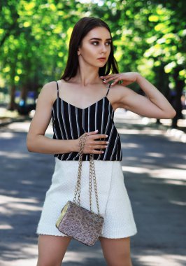 Parkta poz veren genç kız sola bakıyor ve B 'yi koruyor.