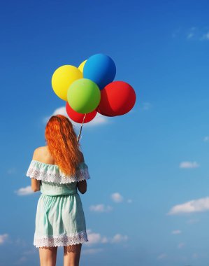 Mavi renkli balonları olan genç bir kızıl kız.