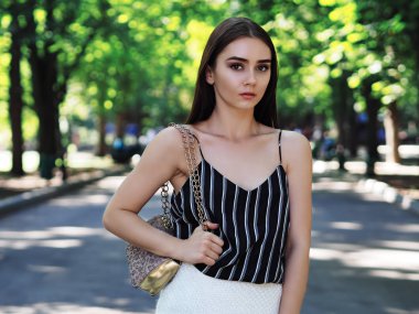 Parkta poz veren genç bir kız model kameraya bakıyor.