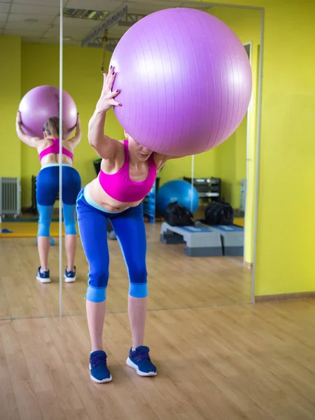 Jong model meisje maakt oefeningen in de sportschool in de voorkant van spiegel — Stockfoto