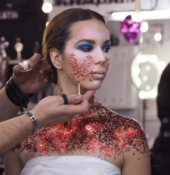 Make-up artist makes make-up at the young models face and drawin
