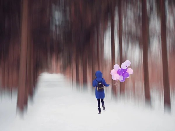 Mladá dívka v modrém kabátě s balónky v lese — Stock fotografie