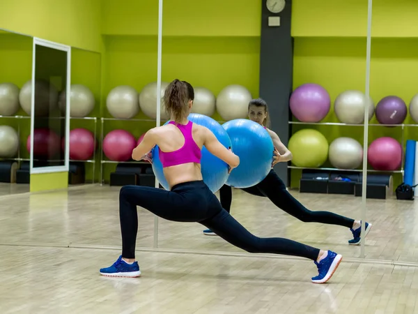 Chica modelo joven hace ejercicios en el gimnasio frente al espejo — Foto de Stock