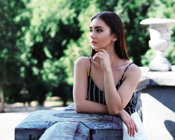 Chica joven modelo posando en el parque de pie cerca del monumento y l —  Fotos de Stock