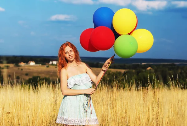 Girl redhead standing with ballons at the yellow spikelets and b — Stock Photo, Image