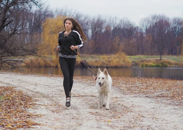 Ormanda koşan köpeği olan genç bir kız.