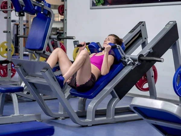 Young model girl makes exercises at the gym in front of mirror — Stock Photo, Image