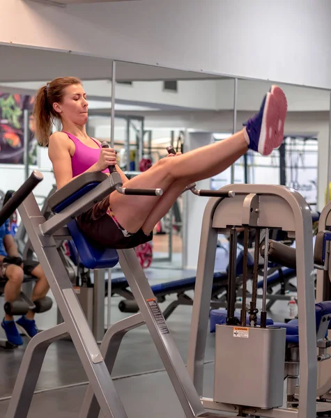 Chica modelo joven hace ejercicios en el gimnasio frente al espejo — Foto de Stock