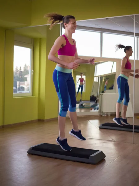 Chica modelo joven hace ejercicios en el gimnasio frente al espejo — Foto de Stock