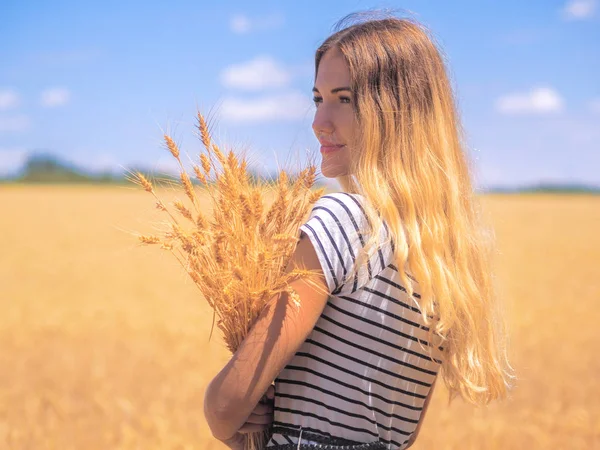 Ung kvinna på vetefältet under den blå himlen vid soliga d — Stockfoto