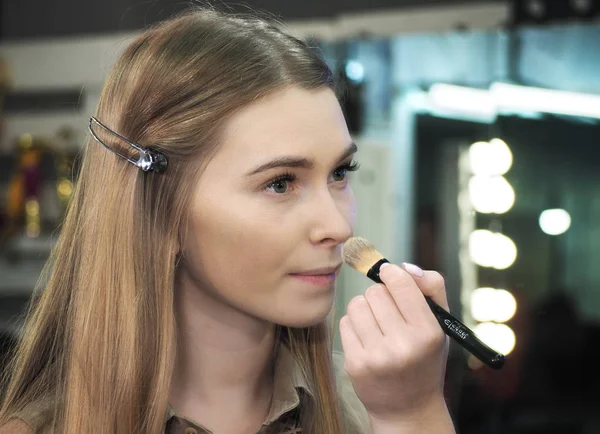 Výtvarník make-up si dělá make-up na tváři a dívá se na mír — Stock fotografie