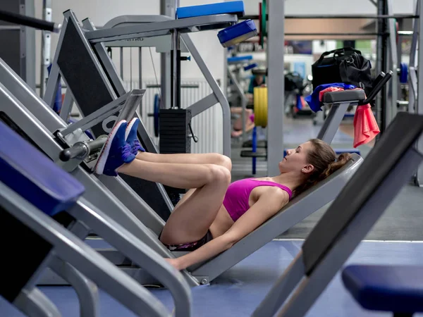 Chica modelo joven hace ejercicios en el gimnasio frente al espejo — Foto de Stock