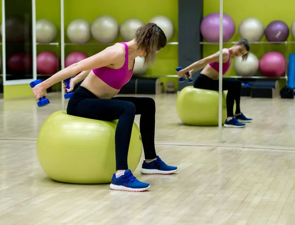 Jong model meisje maakt oefeningen in de sportschool in de voorkant van spiegel — Stockfoto