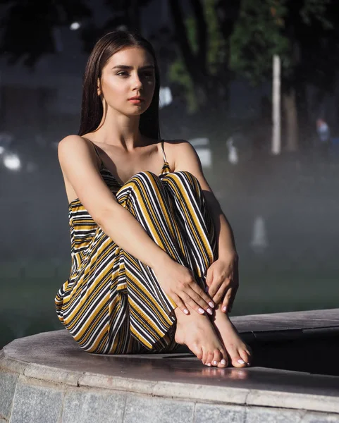 Mädchen brünette modell sitzen in der nähe mit brunnen — Stockfoto