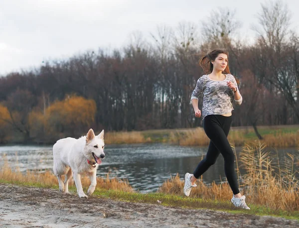 Ormanda koşan köpeği olan genç bir kız.