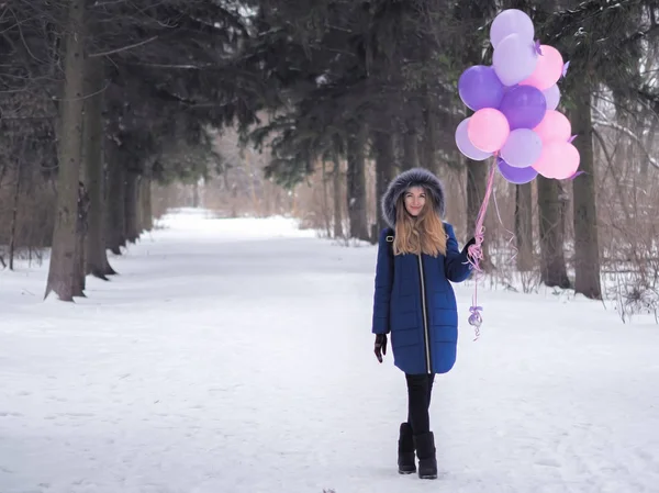 Młoda dziewczyna w niebieskim płaszczu z balonami w lesie — Zdjęcie stockowe