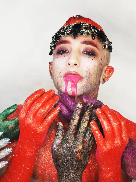 Man model at the red art make-up wears a black crown  looking at