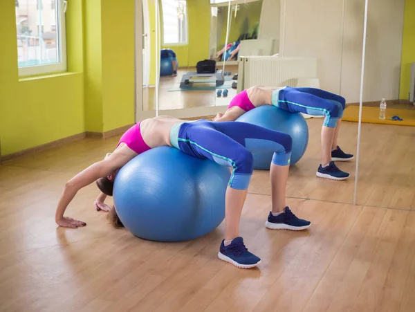 Young model girl makes exercises at the gym in front of mirror — Stock Photo, Image