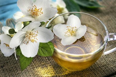 Yasemin çayı ve ahşap eski arka plan üzerinde Yasemin çiçekleri