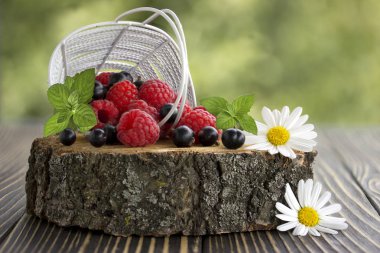 Taze ahududu ve siyah frenk üzümü sepeti yakın planda.