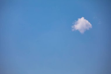 Mavi gökyüzü arka planında izole edilmiş küçük beyaz bulutlu nadir bir sahne, metin için boş alan