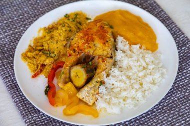 Geleneksel Brezilya balığı moqueca taze sarı hake balığı filetosu, Cynoscion akoupa, farofa, piro ve beyaz pirinçli. Pescada amarela ve dende yağı.