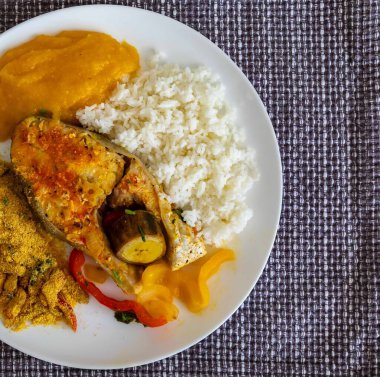 Geleneksel Brezilya balığı moqueca taze sarı hake balığı filetosu, Cynoscion akoupa, farofa, piro ve beyaz pirinçli. Pescada amarela ve dende yağı.