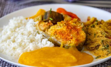 Geleneksel Brezilya balığı moqueca taze sarı hake balığı filetosu, Cynoscion akoupa, farofa, piro ve beyaz pirinçli. Pescada amarela ve dende yağı.