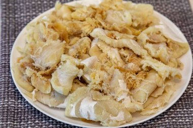 Tuzlanmış ve kurutulmuş, yuvarlak beyaz bir tabakta, gadus makrosefalus morina filetosu parçaları.