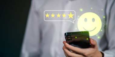 Beş yıldızlı derecelendirme ve gülümseyen emoji ile müşteri memnuniyeti kavramı, mükemmel hizmeti, olumlu geri bildirimi ve dijital iletişim ve çevrimiçi inceleme sistemlerindeki iş başarısını simgeliyor.