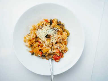 Makarna ve peynir beyaz tabakta sebze ile