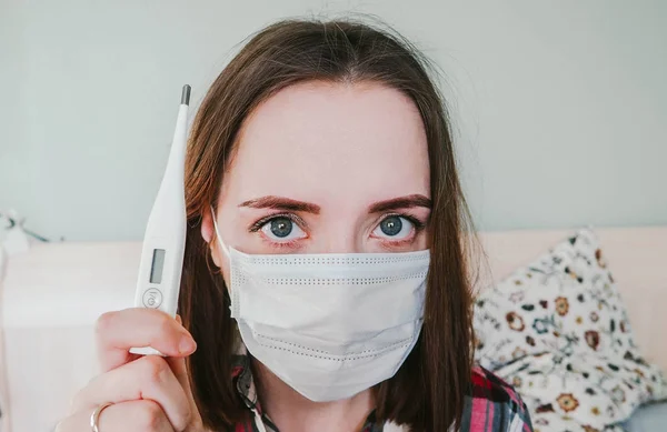 Mädchen in Krankenhausmaske mit Thermometer in der Hand Stockfoto