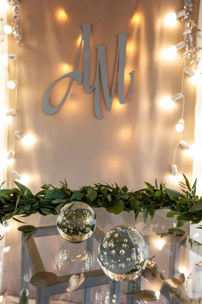 Decoration of wedding registration desk. Glass sphere, strings of lights and wreath of leaves