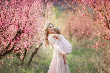 Gül bahçesinde çiçekler ağaçlar bulunan bir bebek ile anne