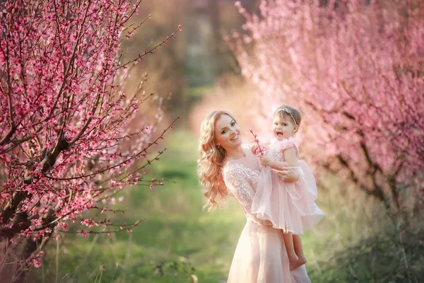 Mãe com uma criança no jardim de rosas com árvores de flores — Fotografia de Stock