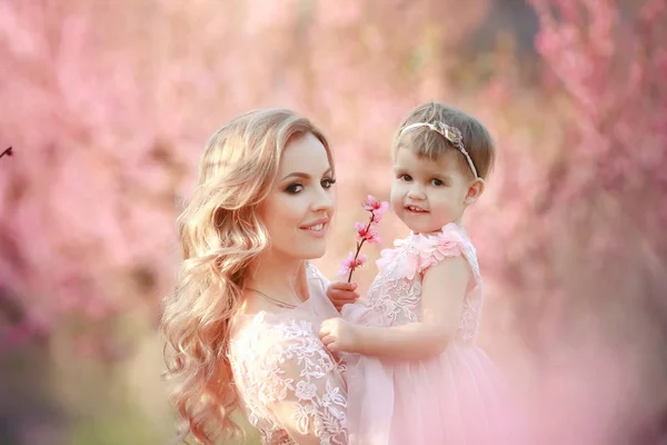 Mom with an infant in the rose garden with flowers trees — Stock Photo, Image