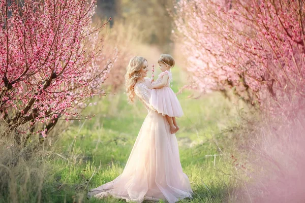 Mamá con un bebé en el jardín de rosas con flores árboles — Foto de Stock