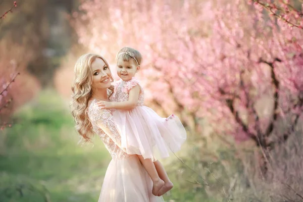 Mãe com uma criança no jardim de rosas com árvores de flores — Fotografia de Stock
