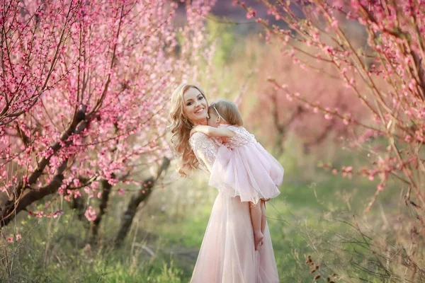 Mãe com uma criança no jardim de rosas com árvores de flores — Fotografia de Stock