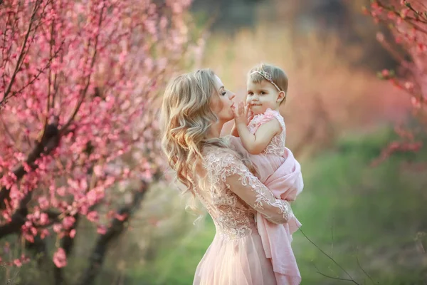 Portrait of young beautiful mother with her little girl. Close up still of loving family. Attractive woman holding her child in pink flowers and smiling — Stock Photo, Image