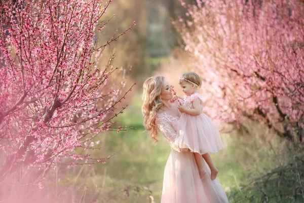 Mãe com uma criança no jardim de rosas com árvores de flores — Fotografia de Stock