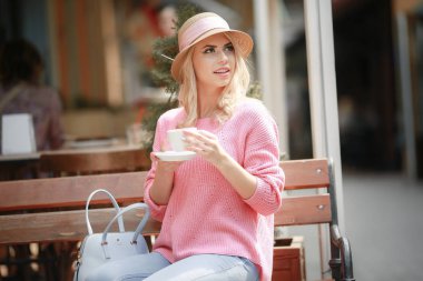 Romantik ruh hali içinde çekici kadın pembe ceket giyen masada otururken mutluluk içinde gülümseyen