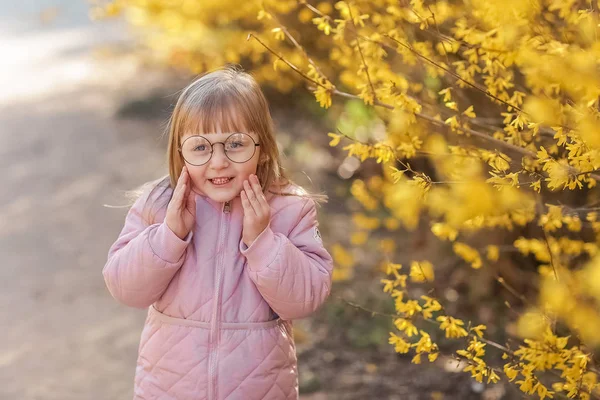 가을 공원에서 트렌디 한 핑크 코트를 입고 세련된 아이 소녀 5-6 세. 카메라를 보고 있습니다. 가을 시즌. 어린 시절. 그녀는 모델로 포즈. — 스톡 사진