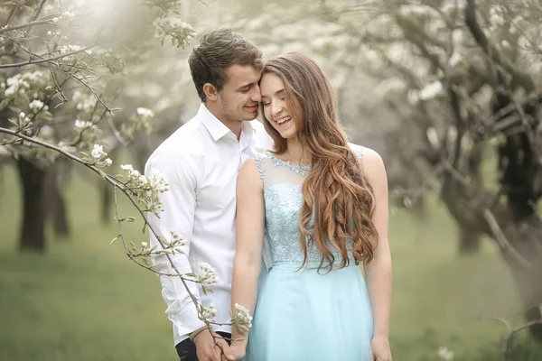 En kysser nygifta par spenderar tid i blommande trädgård. — Stockfoto