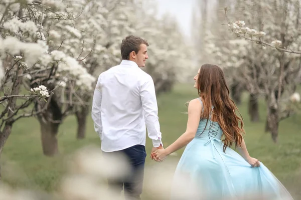 En kysser nygifta par spenderar tid i blommande trädgård. — Stockfoto