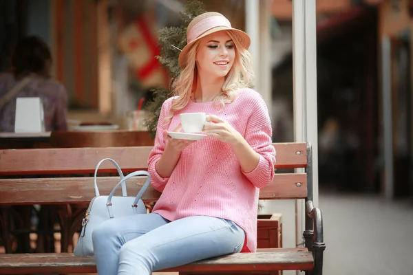 Menina bonita em um vestido rosa sentado em um café com um tablet e uma xícara de cappuccino. Jovem mulher feliz usando computador tablet em um café . — Fotografia de Stock